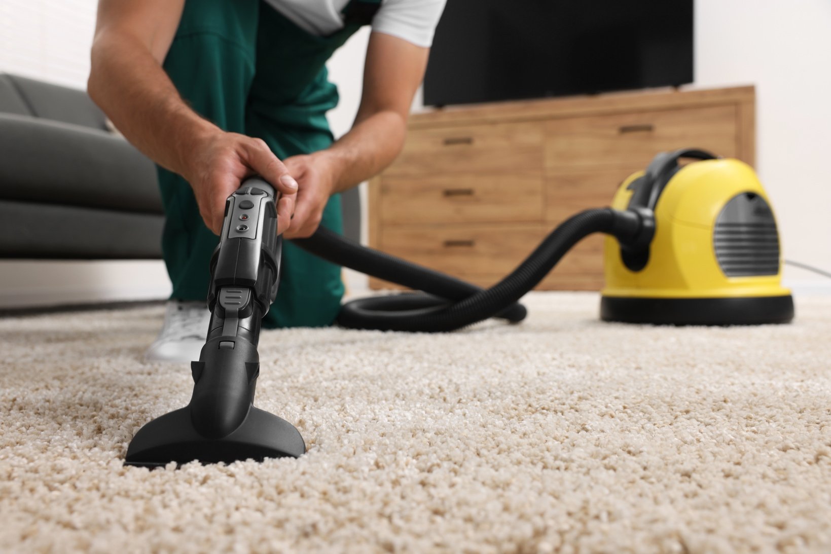 Dry Cleaner's Employee Hoovering Carpet with Vacuum Cleaner Indo